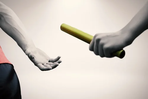 Two people pass a baton to each other